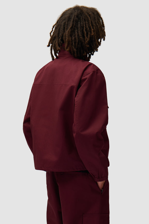 Waxed Ripstop Jacket in Bordeaux worn by a model, half-body back view