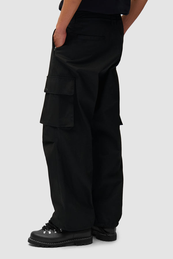 Waxed Ripstop Pants in Black worn by a model, half-body side view