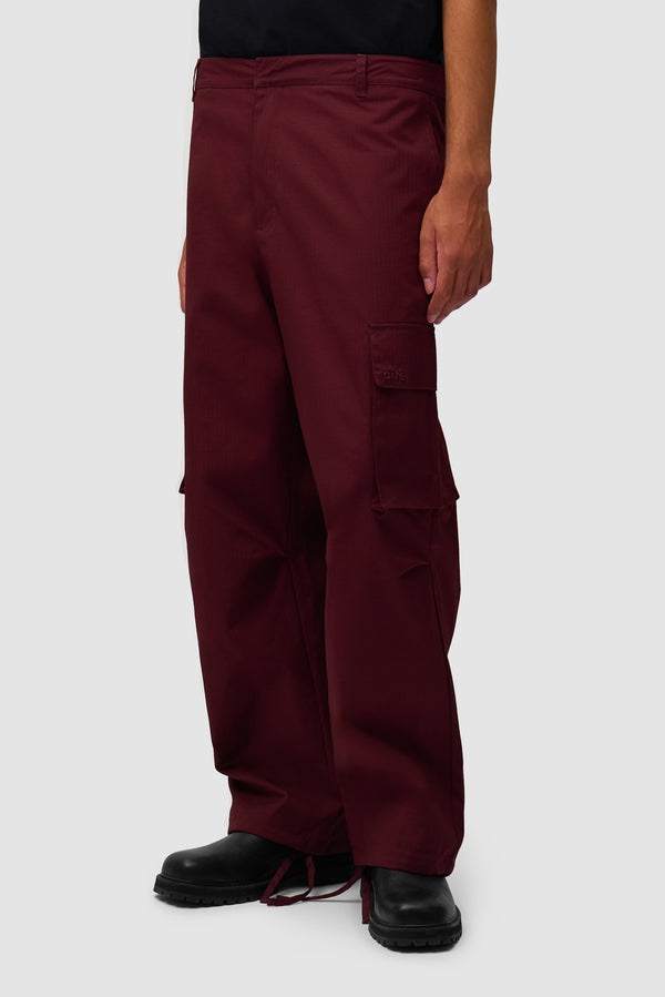 Waxed Ripstop Pants in Bordeaux worn by a model, half-body side view