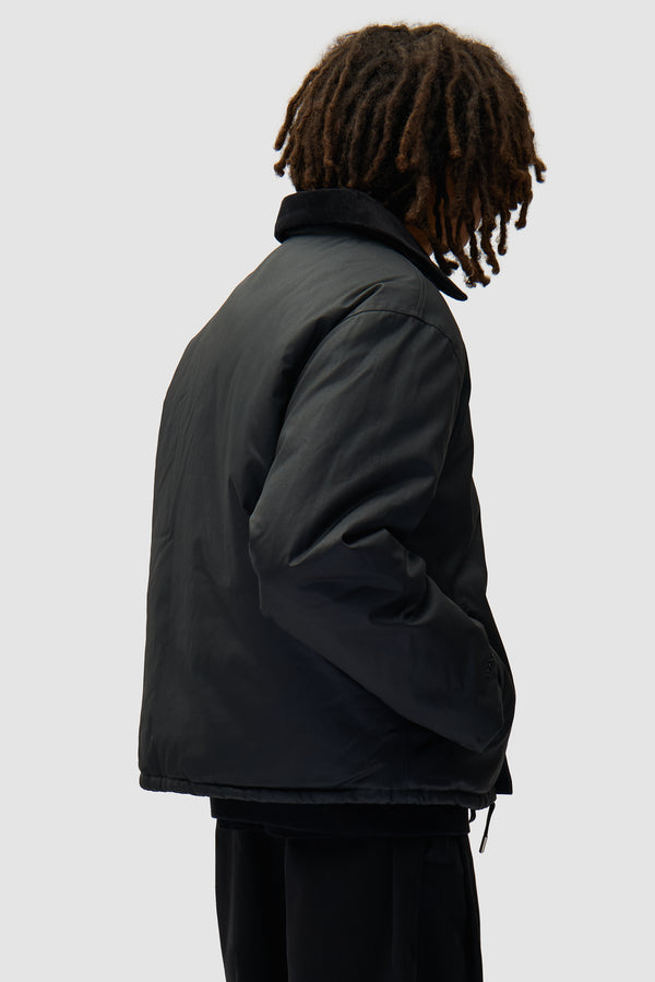 Fireman Jacket in Black worn by a model, half-body back view