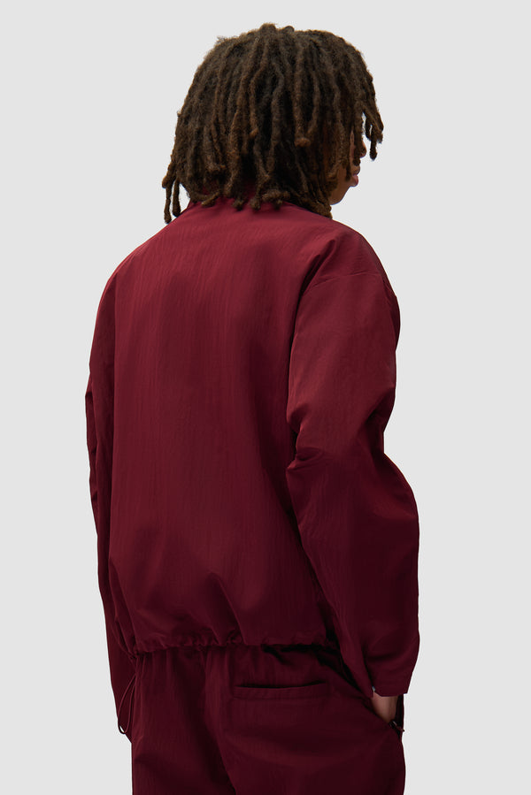 Nylon Track Jacket in Bordeaux worn by a model, half-body back view