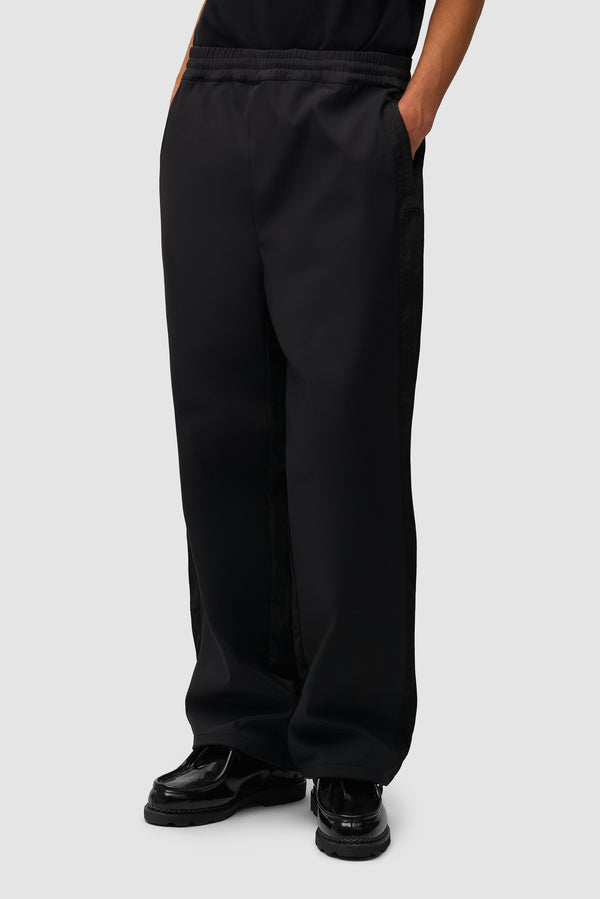 Nylon Track Pants in Black worn by a model, half-body front view