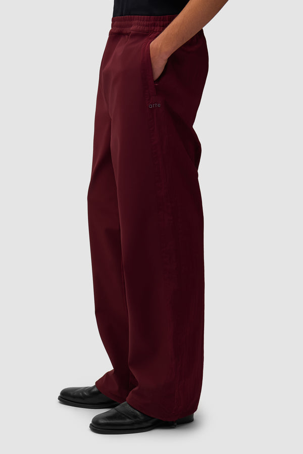 Nylon Track Pants in Bordeaux worn by a model, half-body side view