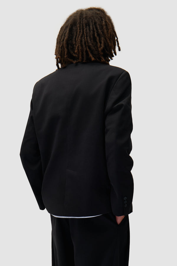 Suit Blazer in Black worn by a model, half-body back view