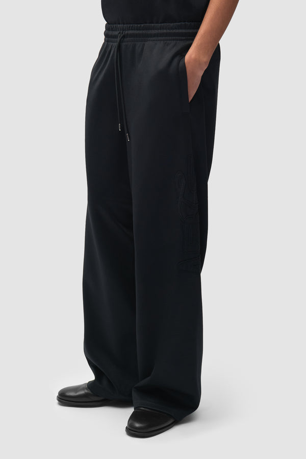 Polyform Nylon Track Pants in Black worn by a model, half-body side view