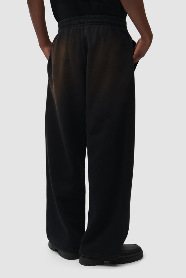 Sunfade Uniform Track Pants in Black worn by a model, half-body back view