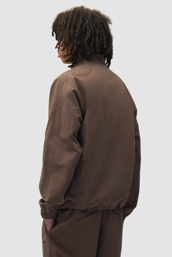 Uniform Track Jacket in Brown worn by a model, half-body back view