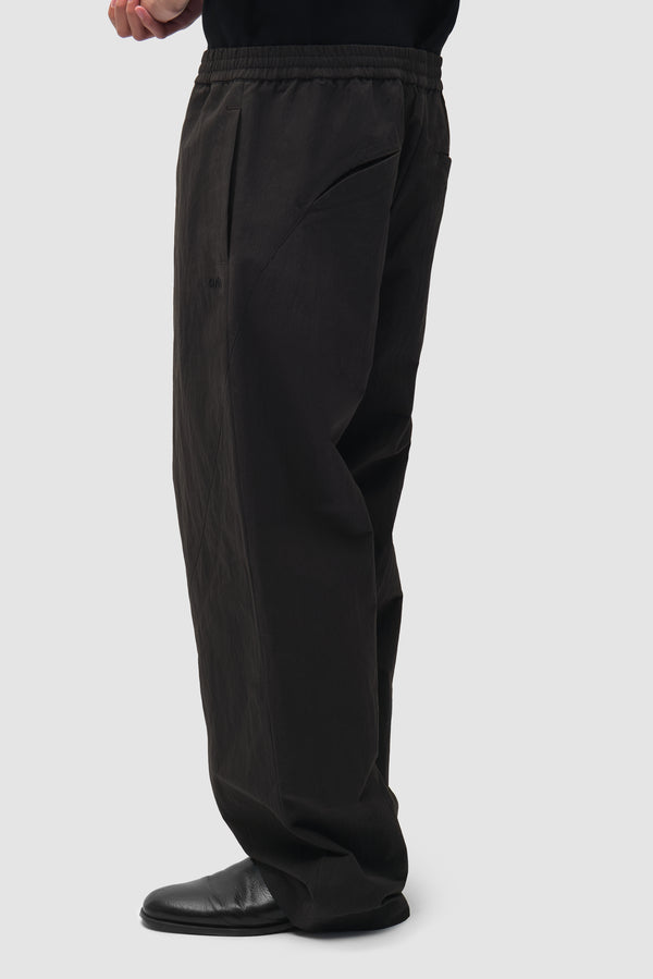 Uniform Track Pants in Black worn by a model, half-body back view