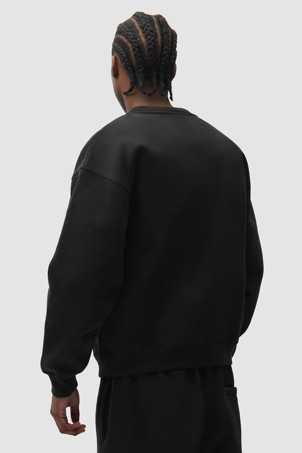 Cor Crewneck in Black worn by a model, half-body back view