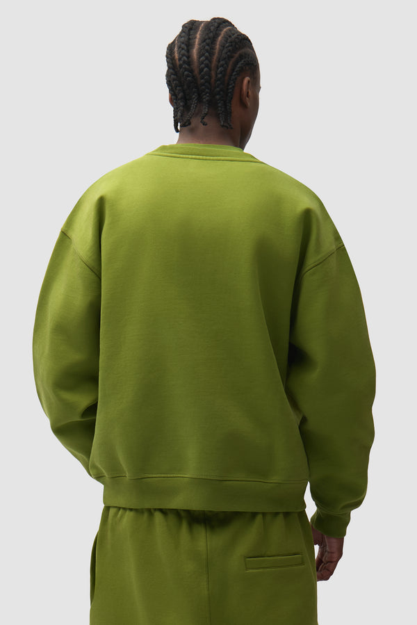 Cor Crewneck in Green worn by a model, half-body back view