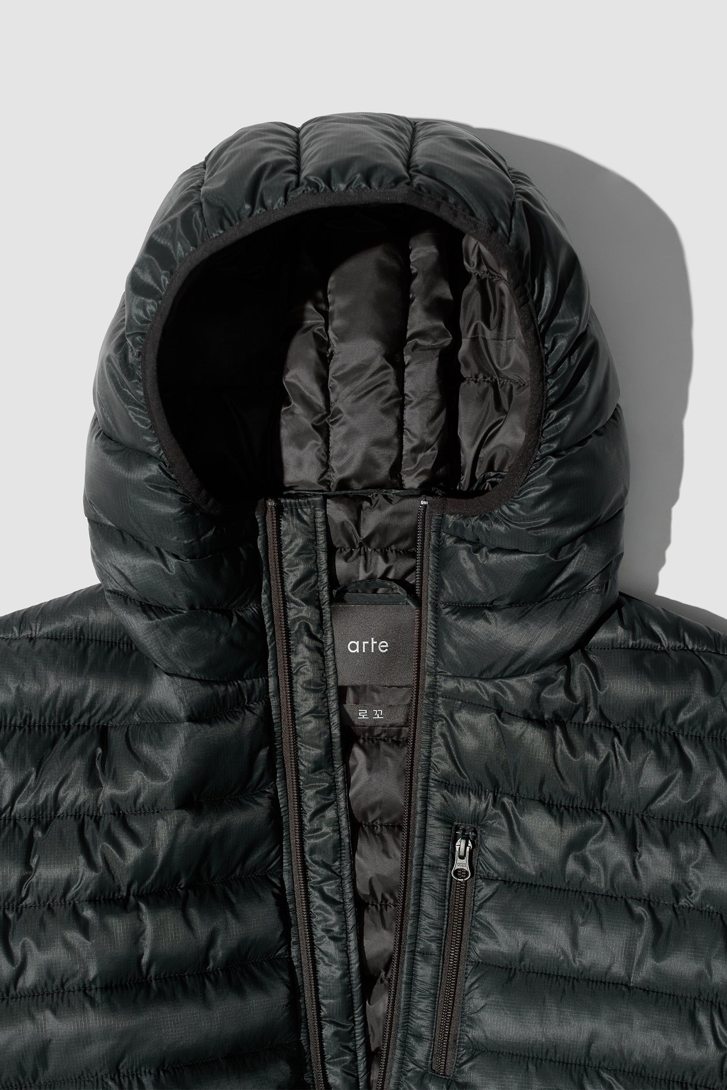 Vue détaillée de la doudoune légère noire, montrant la capuche et le col