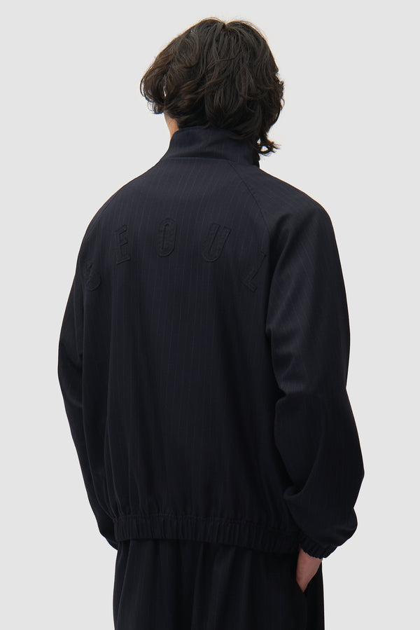 Pinstripe Tracksuit Jacket in Black worn by a model, half-body back view