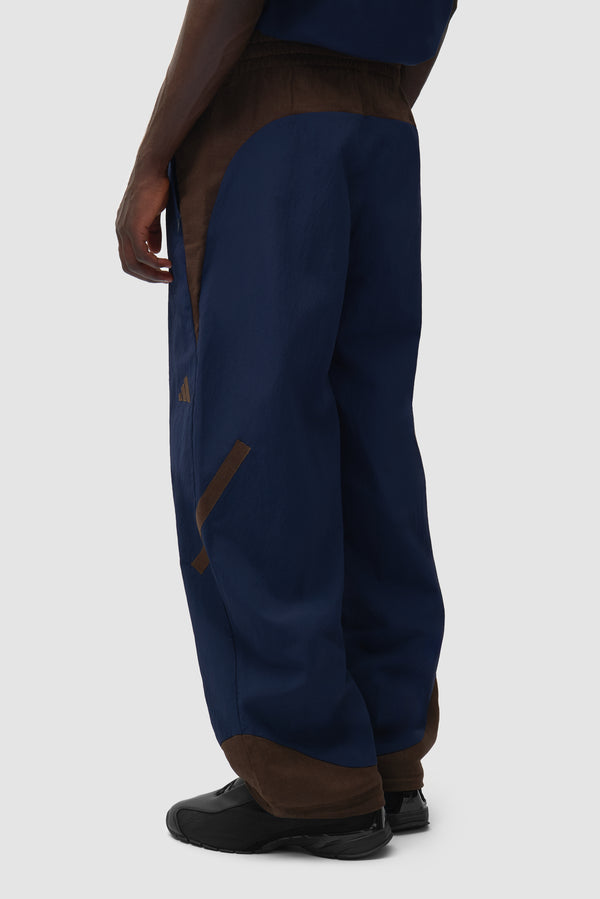 Arte for adidas Z.N.E. track pants in Navy/Brown worn by a model, half-body back view