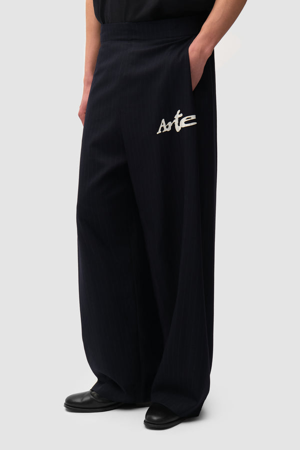 Pinstripe Tracksuit Pants in Black worn by a model, half-body side view