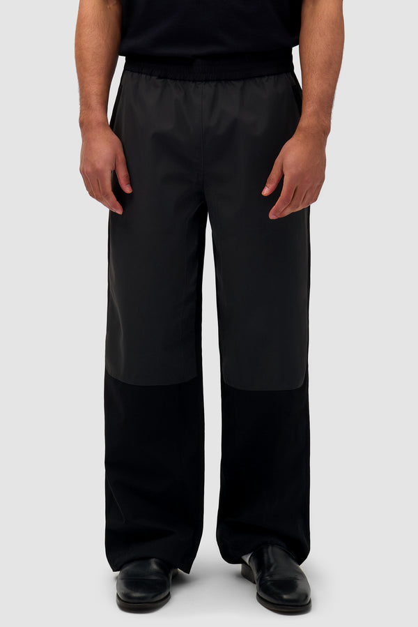 Tracksuit Pants in Black worn by a model, half-body front view