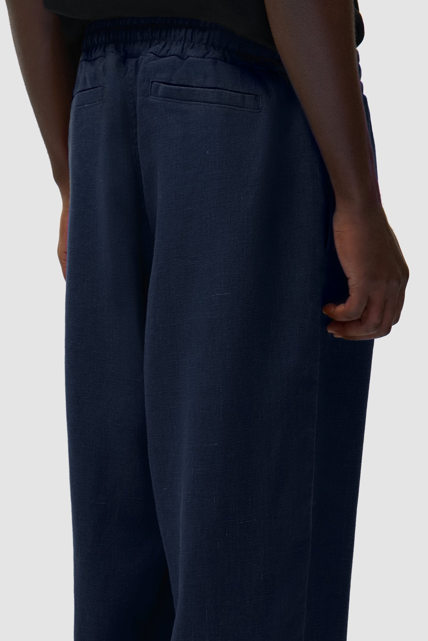 Vue détaillée du pantalon en lin bleu marine, montrant les poches arrière