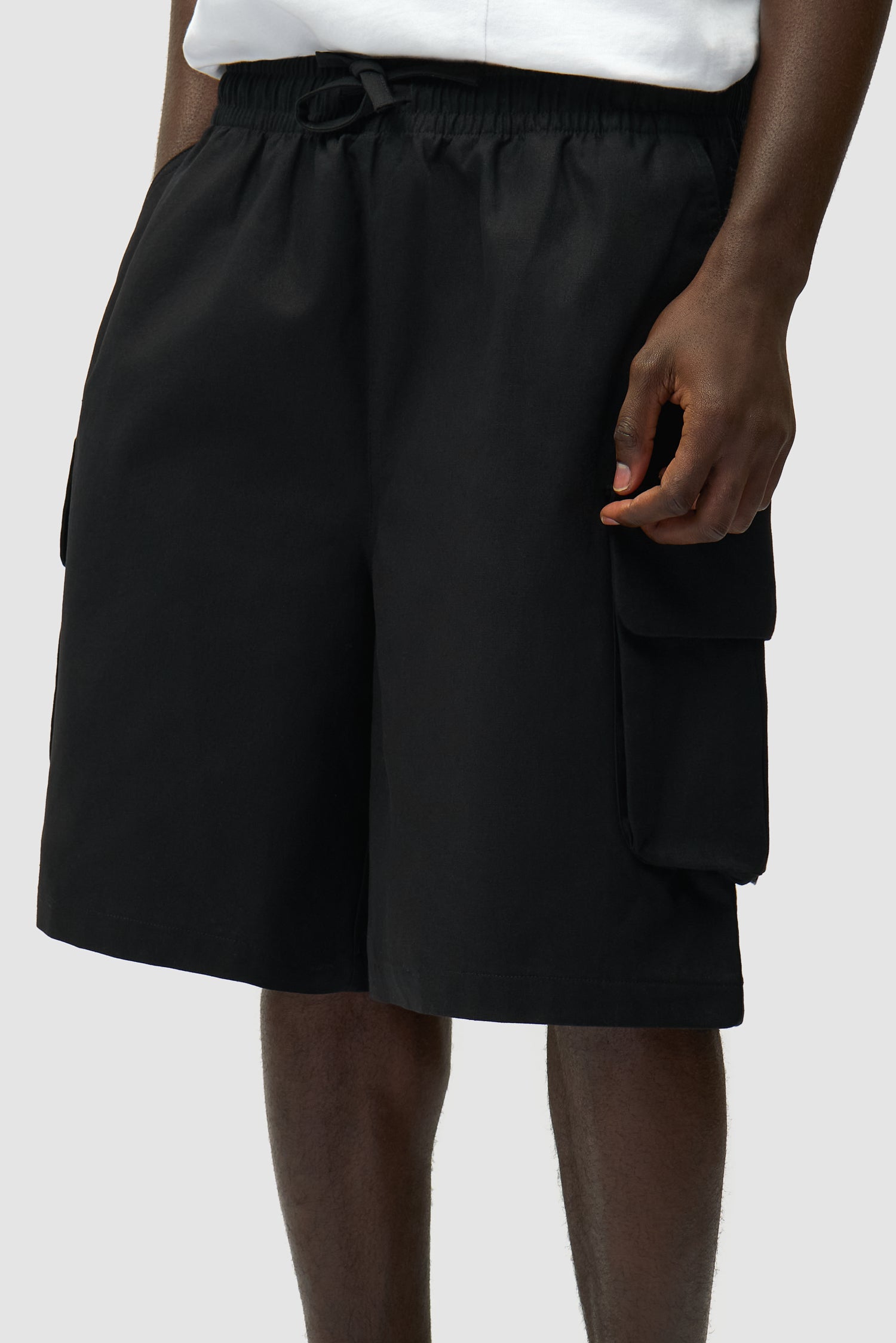 Vue détaillée du short cargo en lin noir, montrant la poche avant