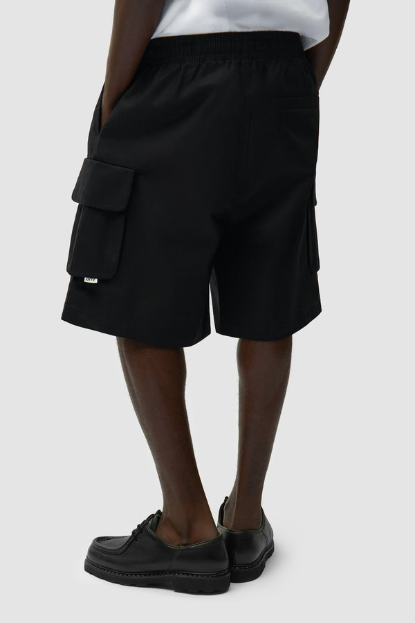 Linen Cargo Shorts in Black worn by a model, half-body side view