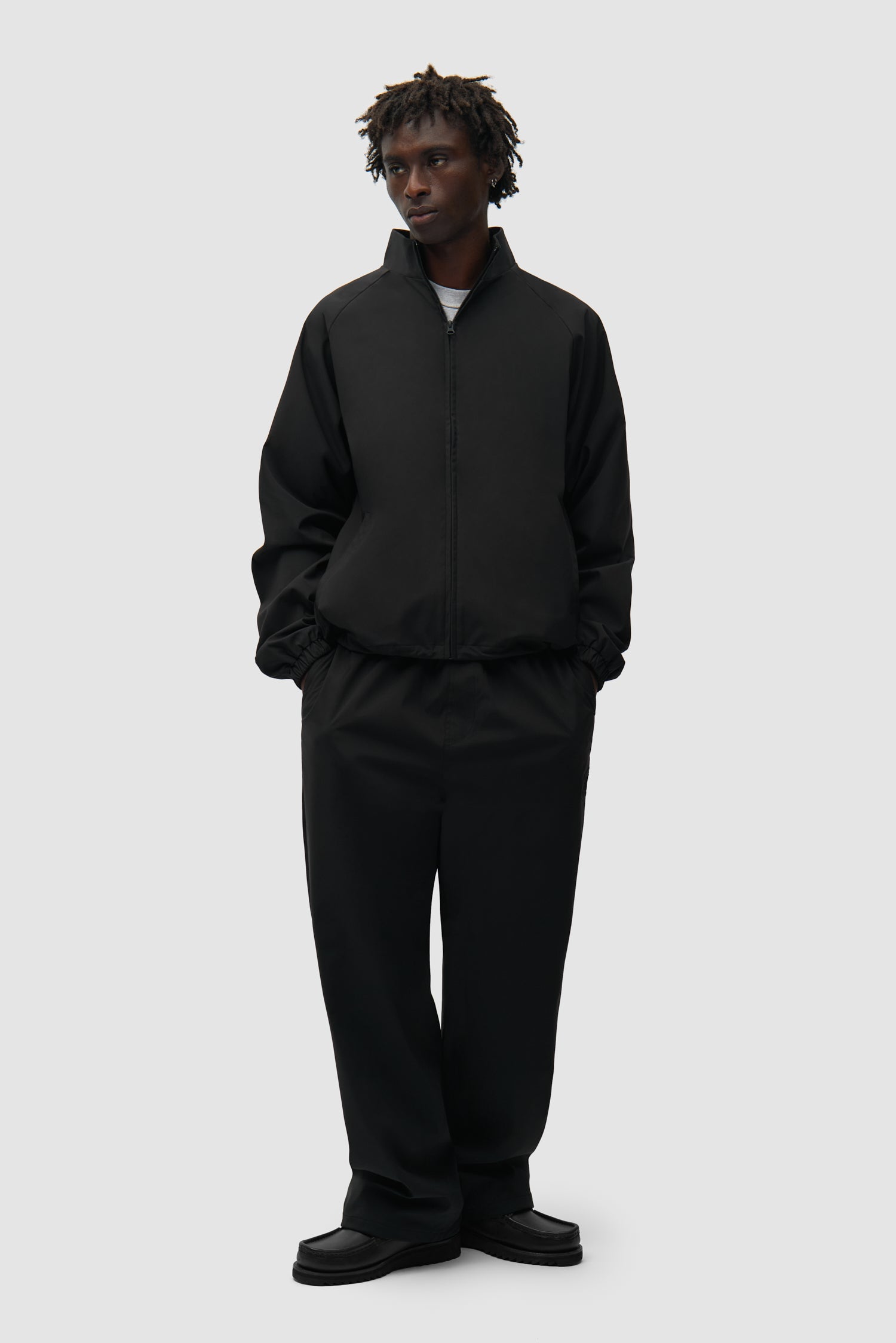 Veste de survêtement de marque noire portée par un mannequin, vue de face en pied