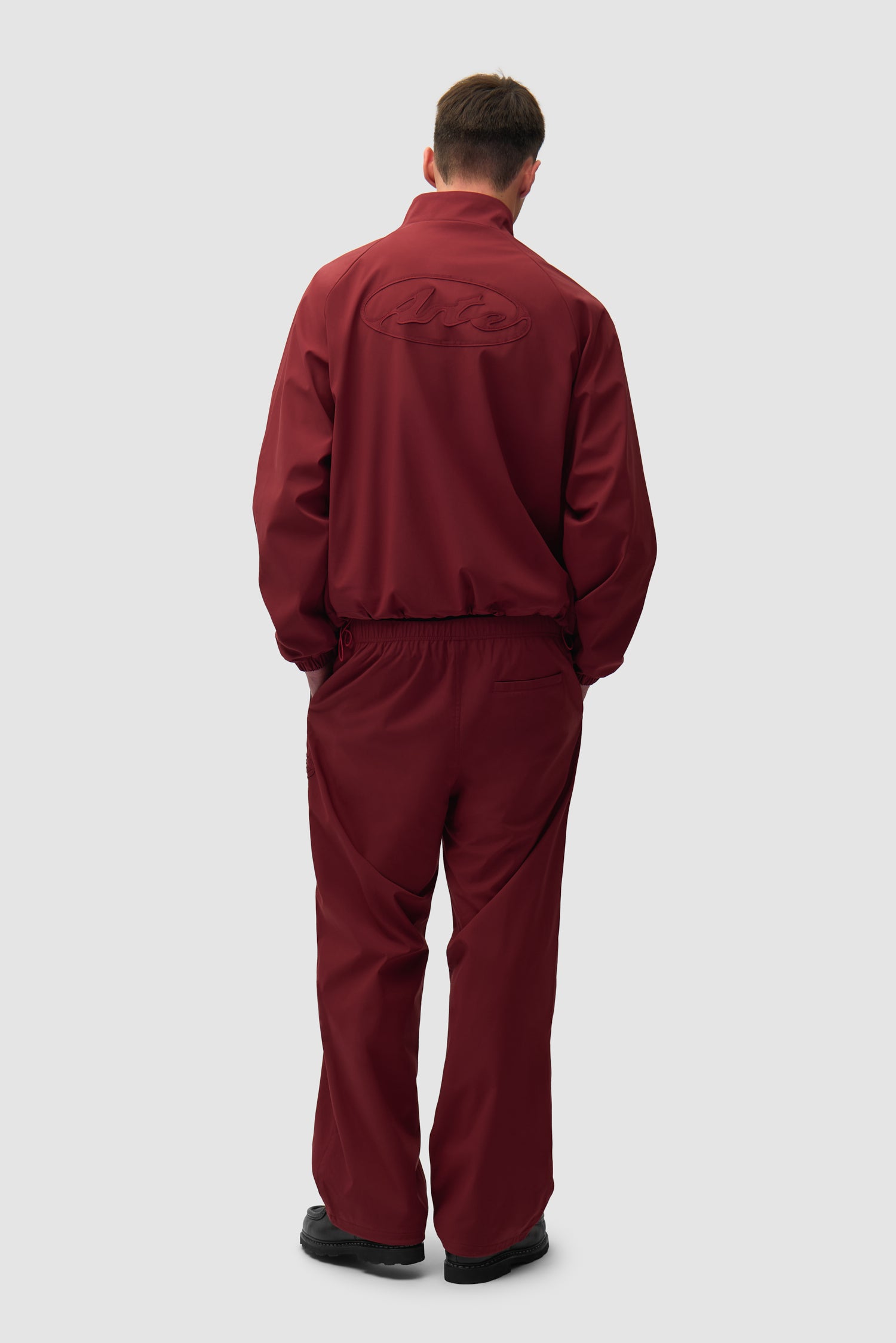 Branded Trackjacket in Bordeaux worn by a model, full-body back view