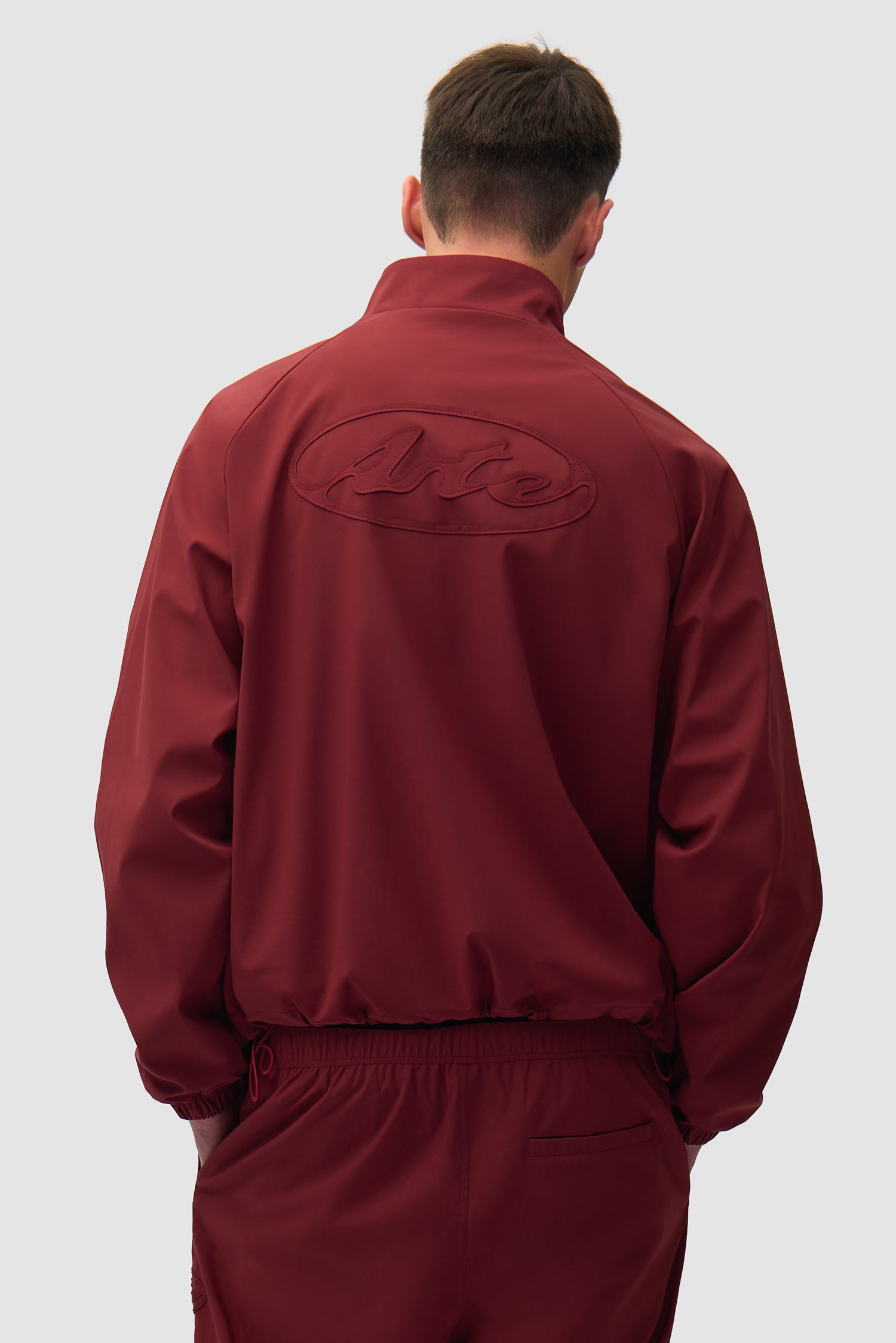 Branded Trackjacket in Bordeaux worn by a model, half-body back view