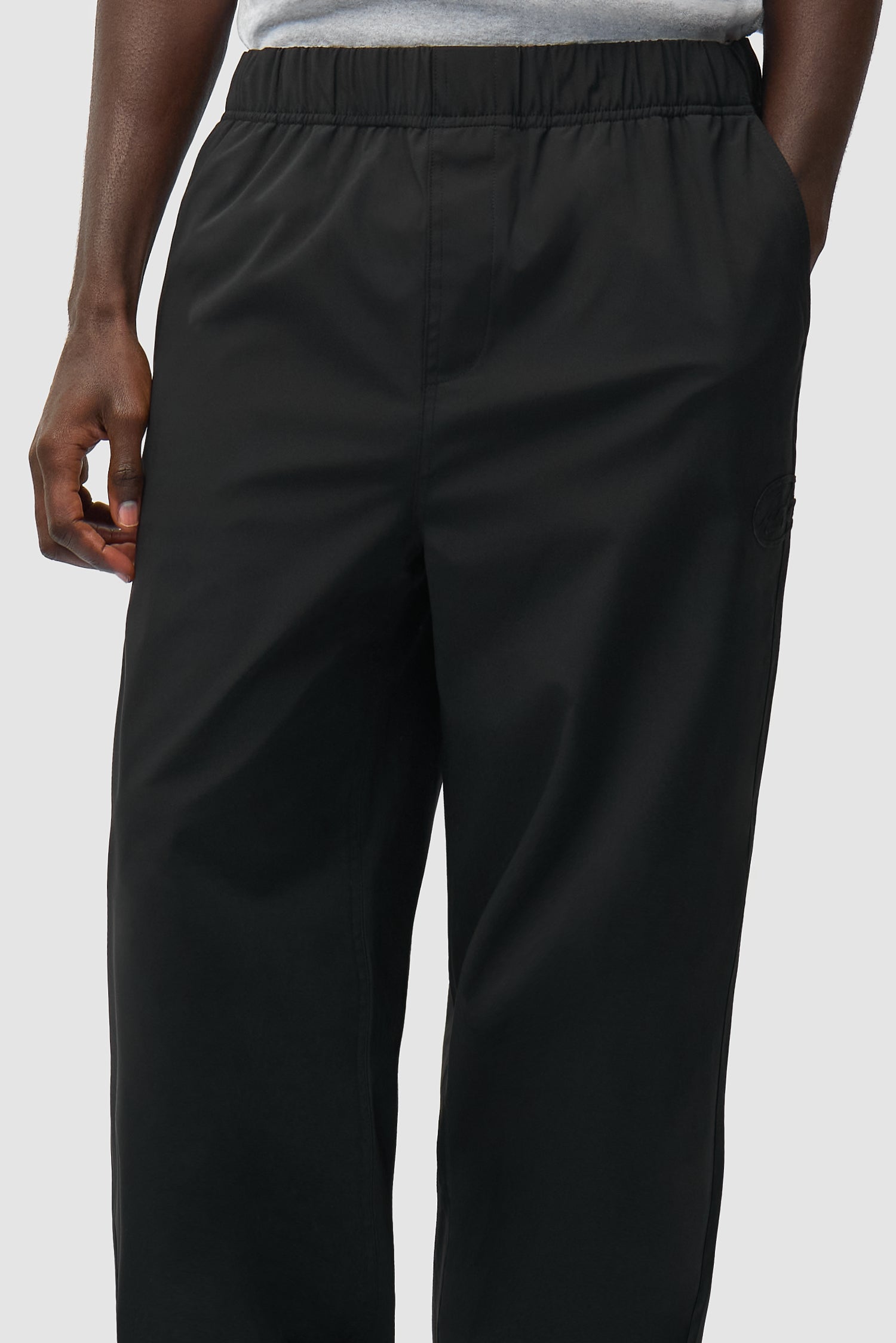 Vue détaillée du pantalon de survêtement de marque noir, montrant l'ourlet avant