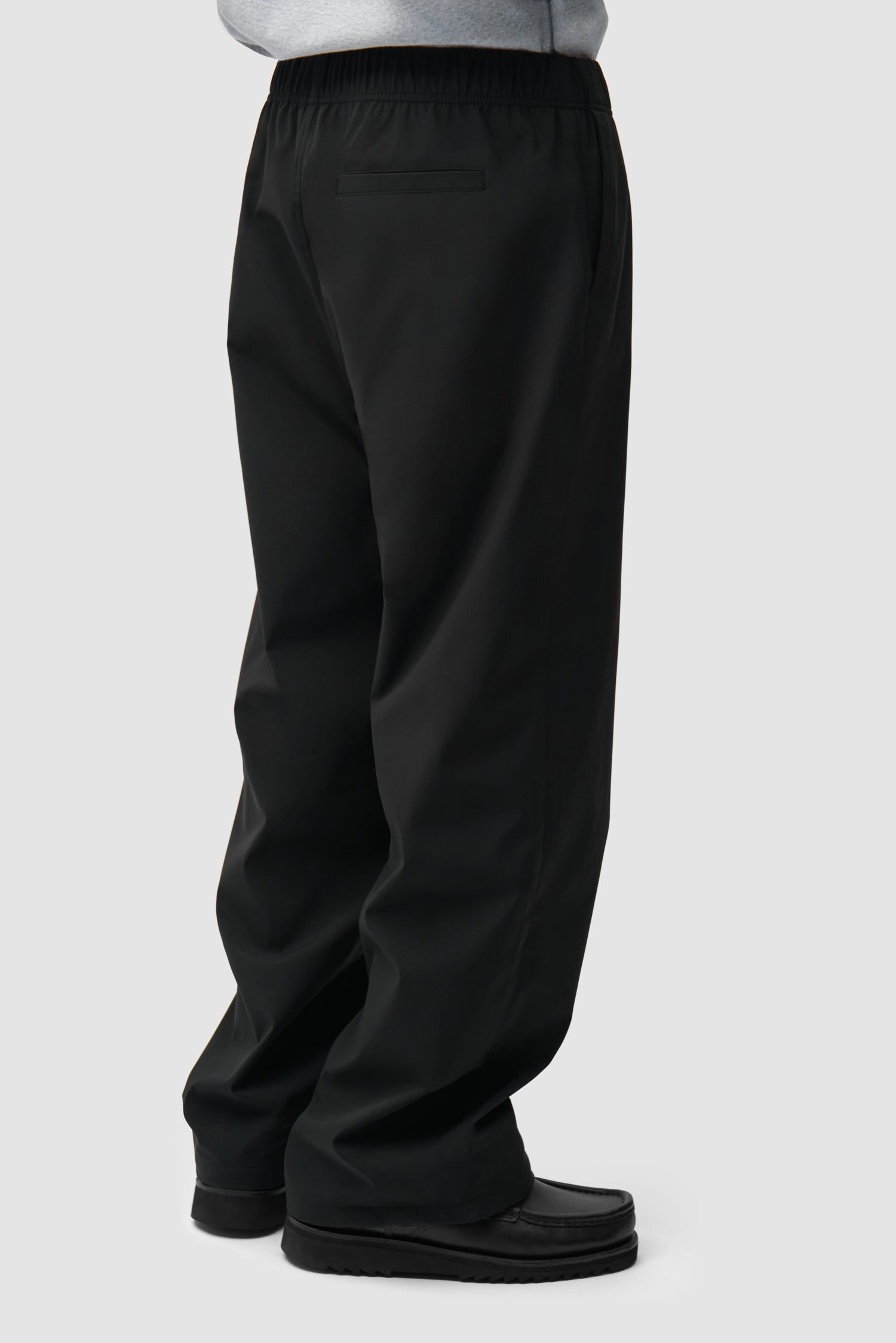 Branded Track Pants in Black worn by a model, half-body back view