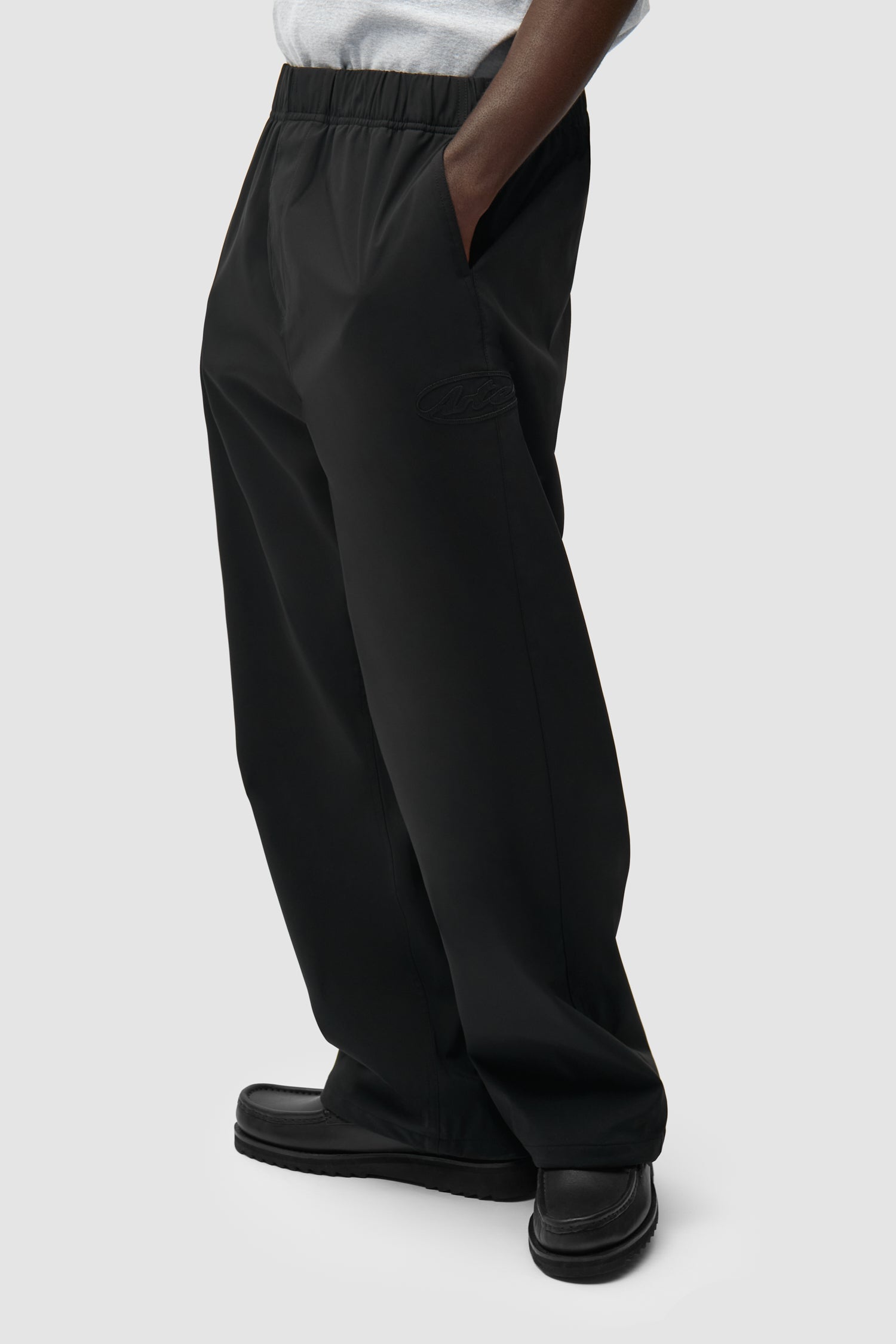 Pantalon de survêtement de marque noir porté par un mannequin, vue de profil à mi-corps