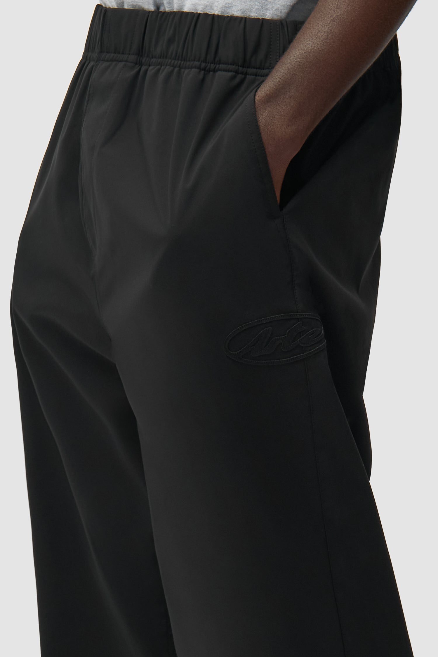 Vue détaillée du pantalon de survêtement de marque noir, avec logo sur le devant