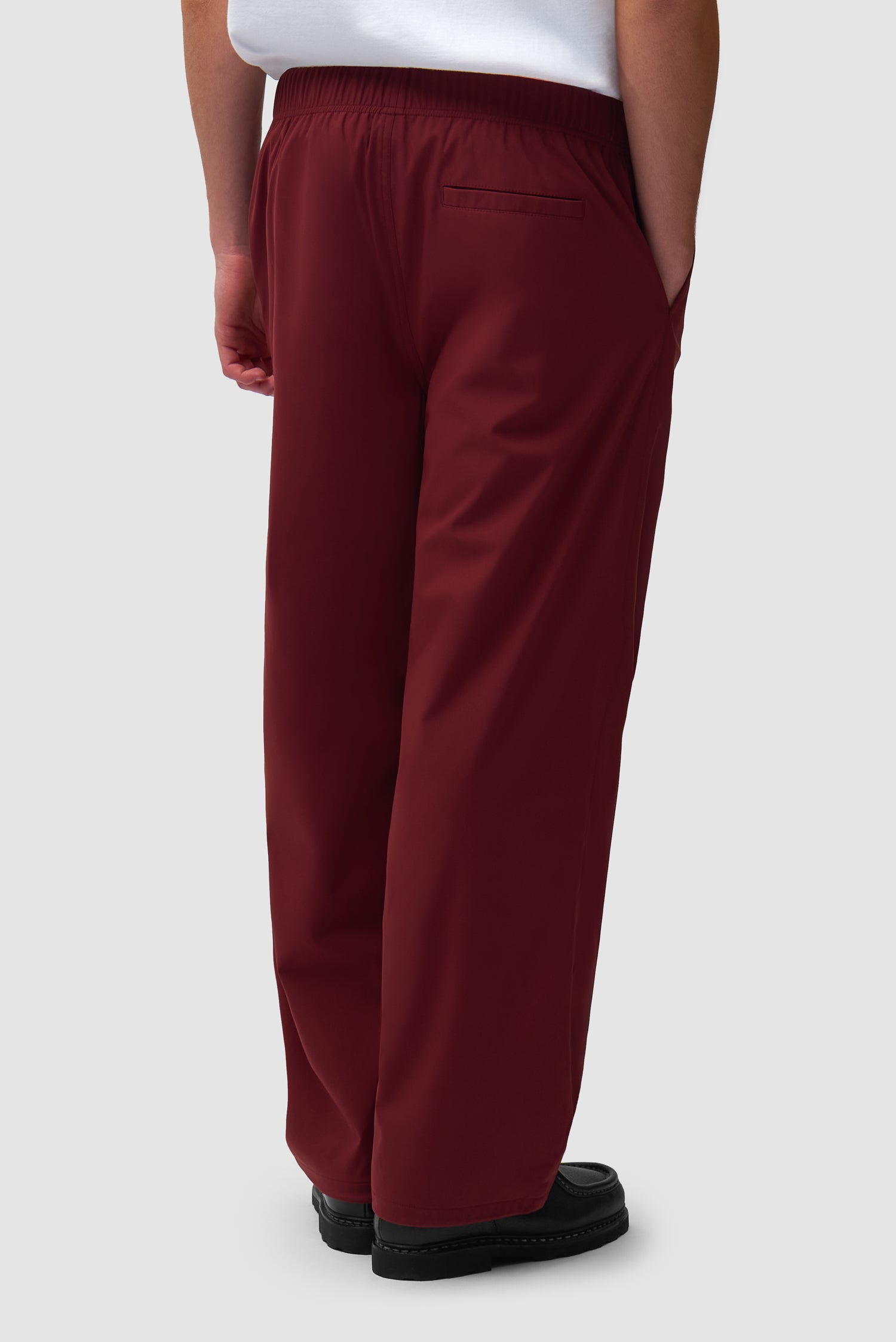 Branded Track Pants in Bordeaux worn by a model, half-body back view