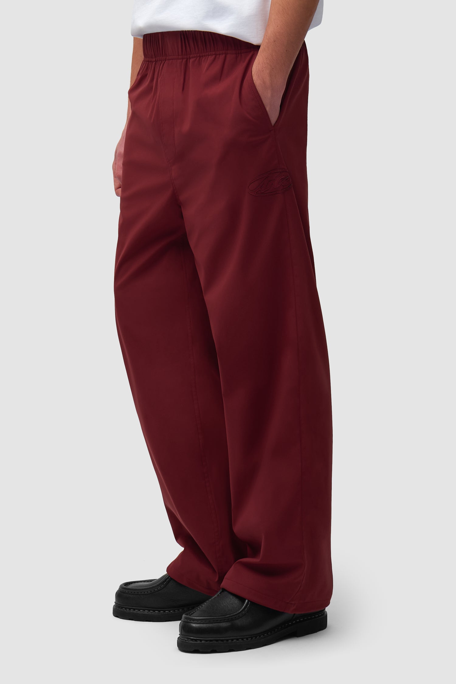 Branded Track Pants in Bordeaux worn by a model, half-body side view