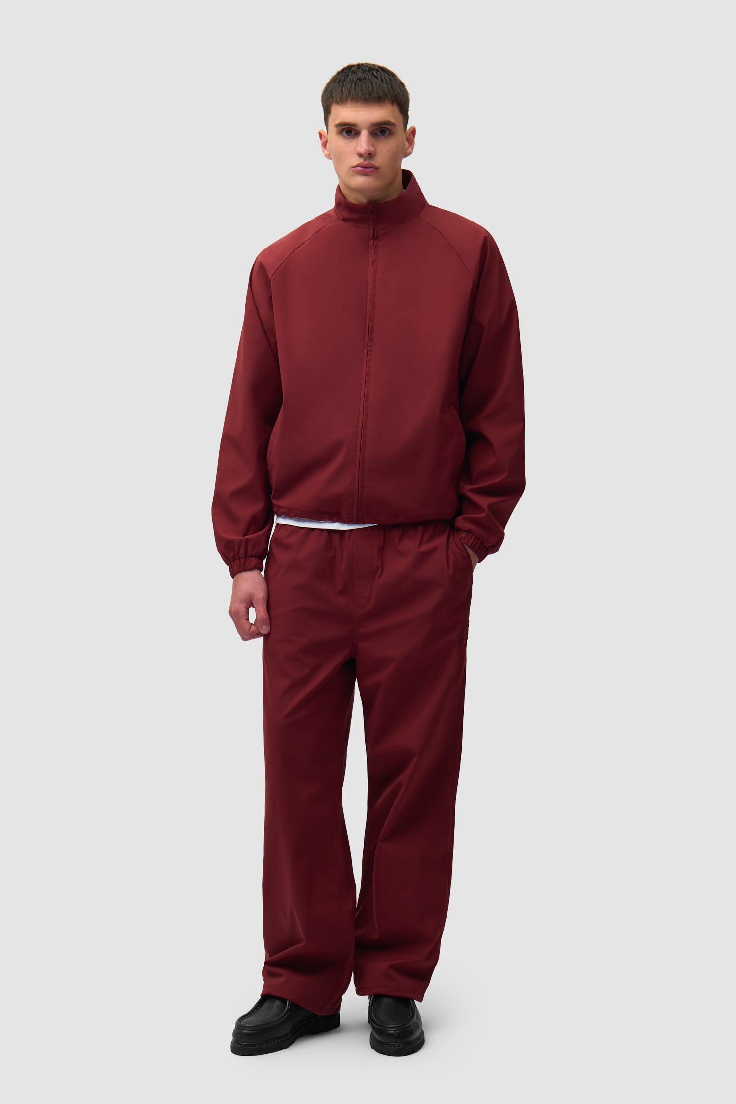 Branded Track Pants in Bordeaux worn by a model, full-body side view