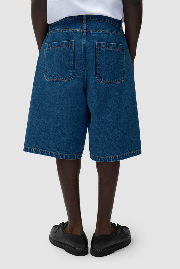Round pocket Denim Shorts in Raw Denim worn by a model, half-body side view