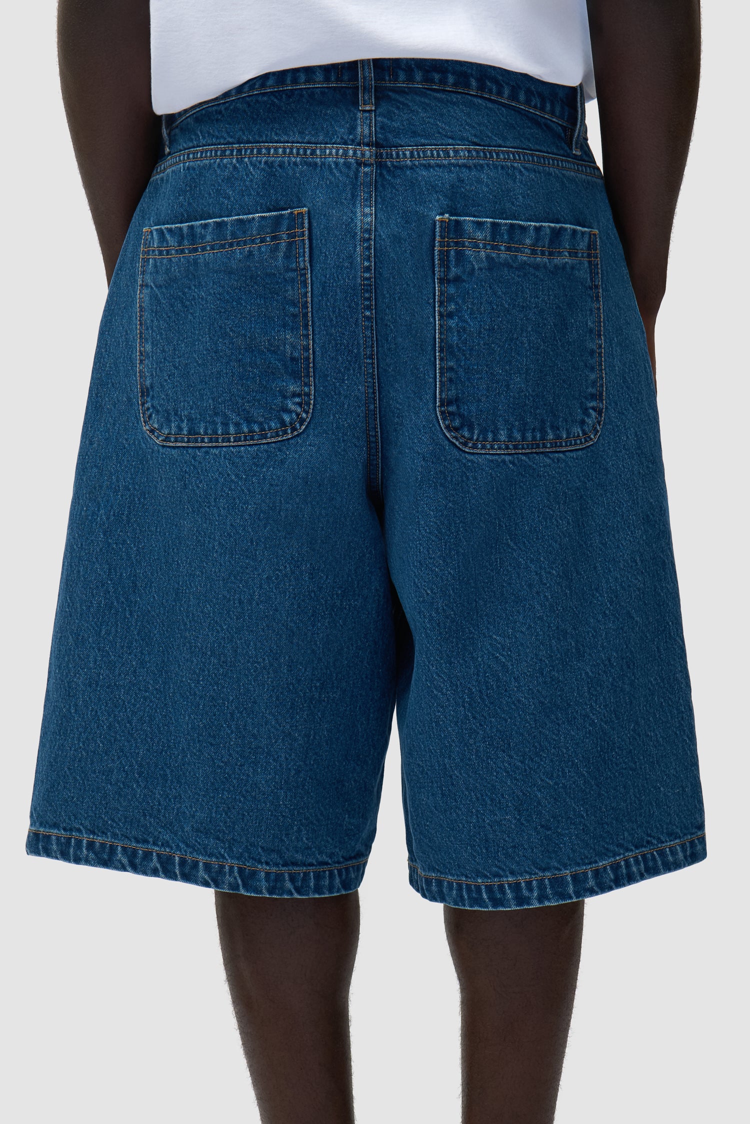 Short en denim à poche ronde en denim brut porté par un mannequin, vue arrière intégrale