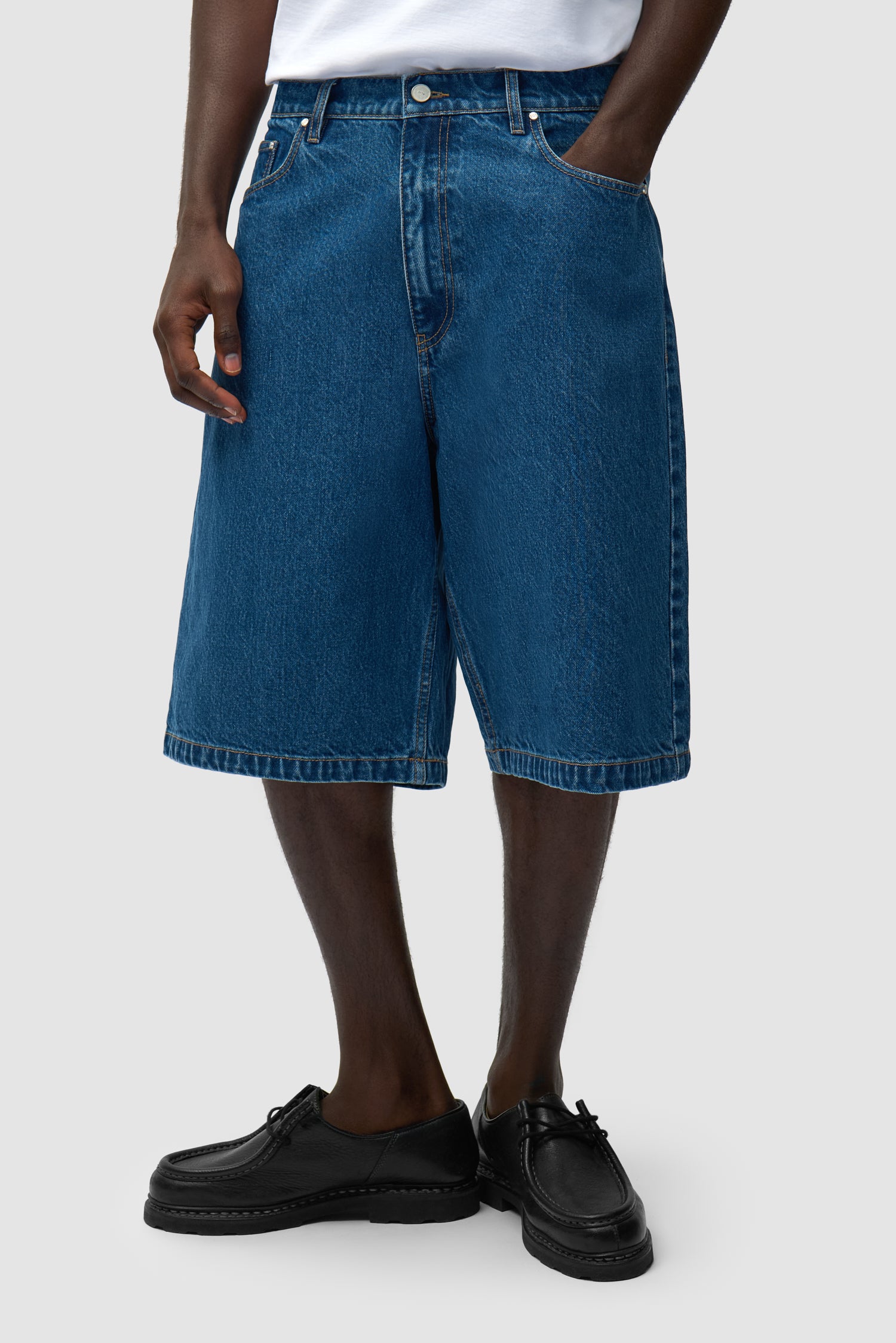 Short en denim brut à poches rondes porté par un mannequin, vue de face en demi-corps