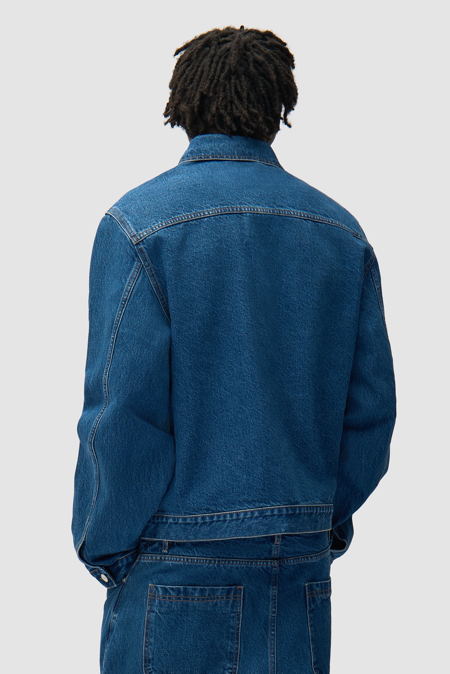 Veste en denim à poches plissées en denim brut portée par un mannequin, vue de dos à mi-corps