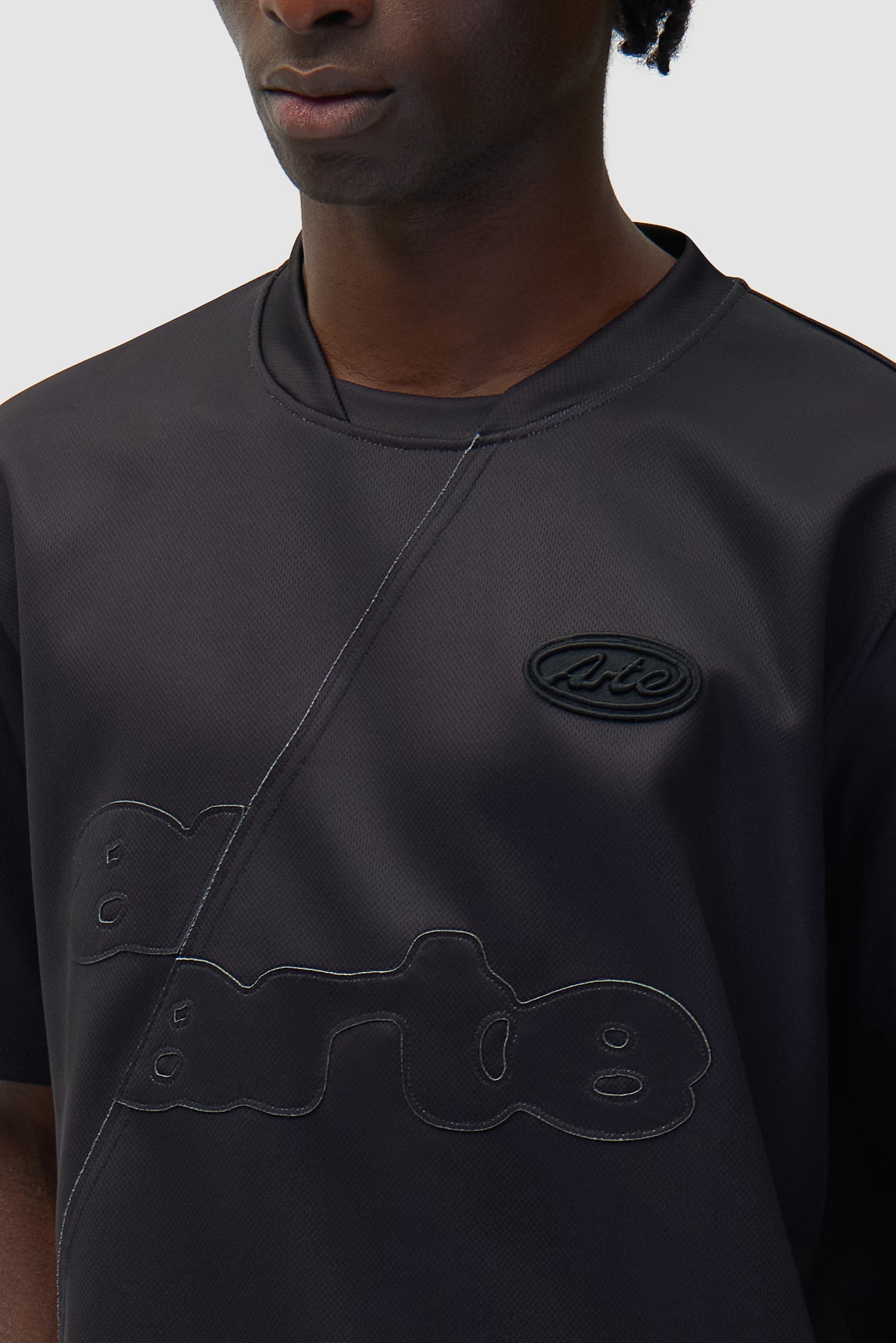 Vue détaillée du t-shirt de football noir, avec logo sur le devant