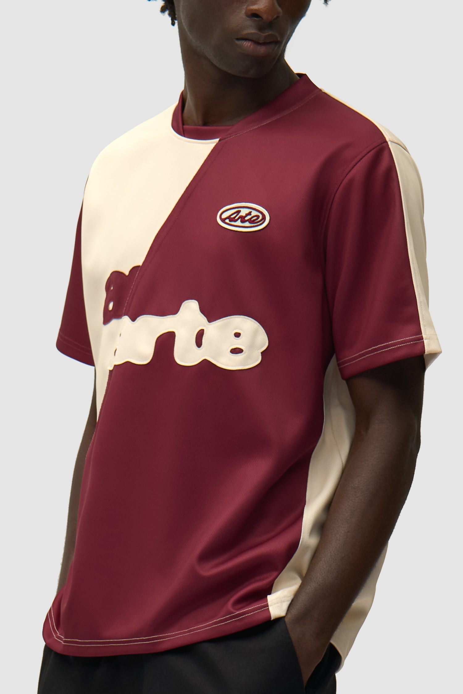 T-shirt de football bordeaux/crème porté par un mannequin, vue de profil à mi-corps