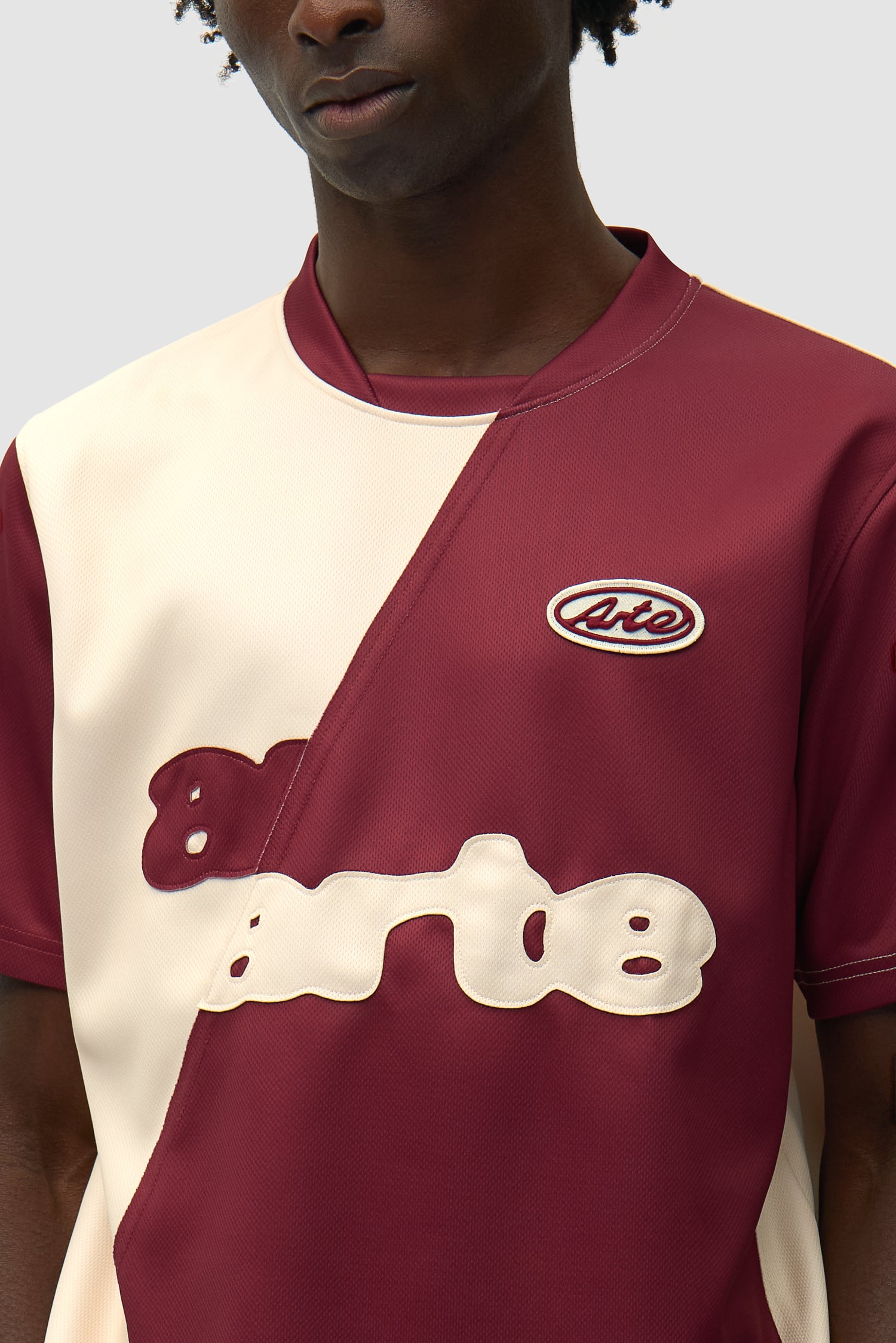 Vue détaillée du t-shirt de football bordeaux/crème, avec logo sur le devant