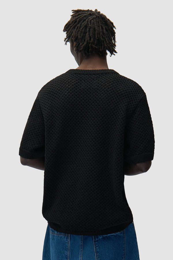 Crochet T-shirt in Black worn by a model, half-body back view
