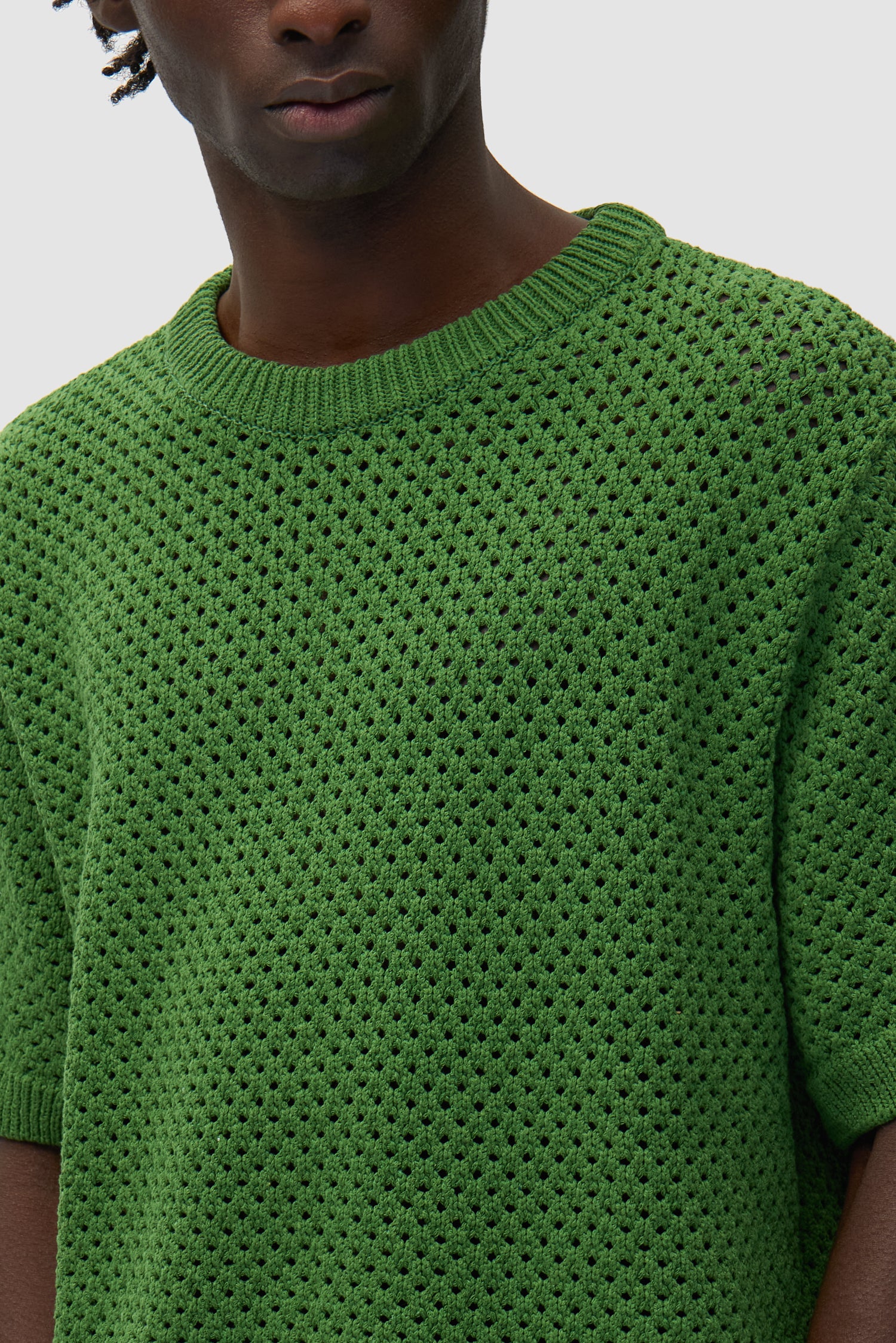 Vue détaillée du t-shirt au crochet vert, montrant le motif tricoté