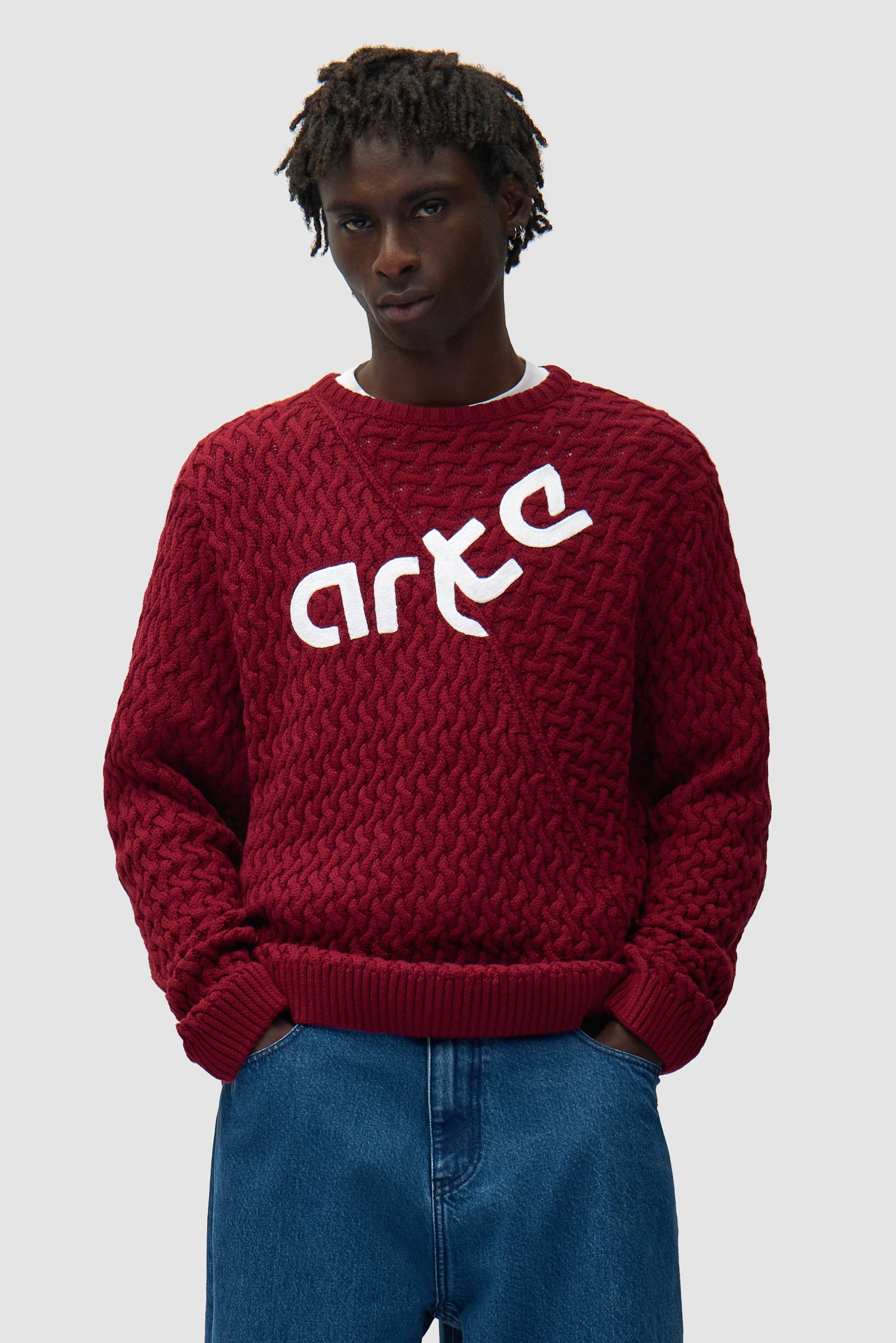 Pull à logo déformé couleur bordeaux porté par un mannequin, vue de face en demi-corps