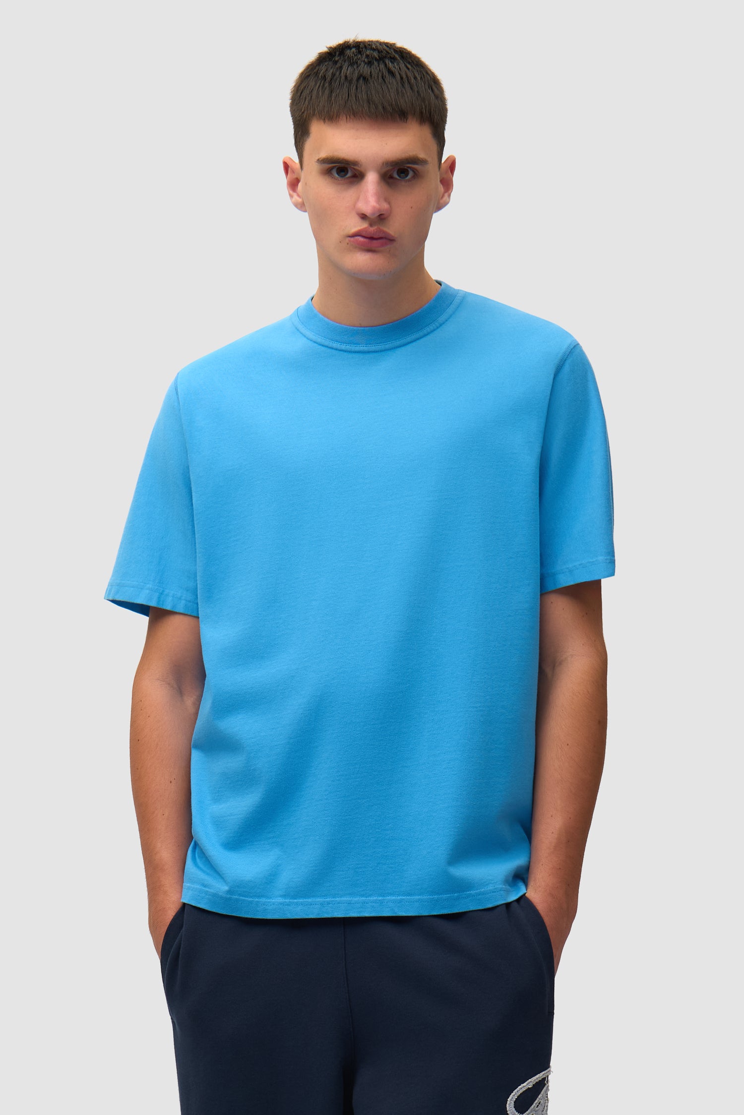 T-shirt SS26 bleu porté par un mannequin, vue de face en demi-corps