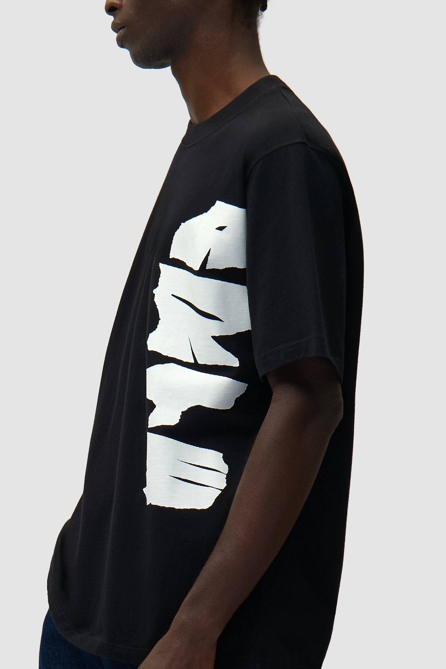 T-shirt noir avec logo sur le côté porté par un mannequin, vue détaillée du demi-corps