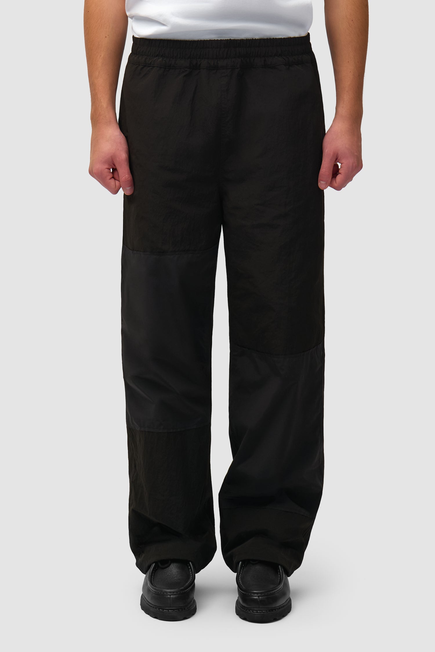 Pantalon de survêtement carré noir porté par un mannequin, vue de face en demi-corps