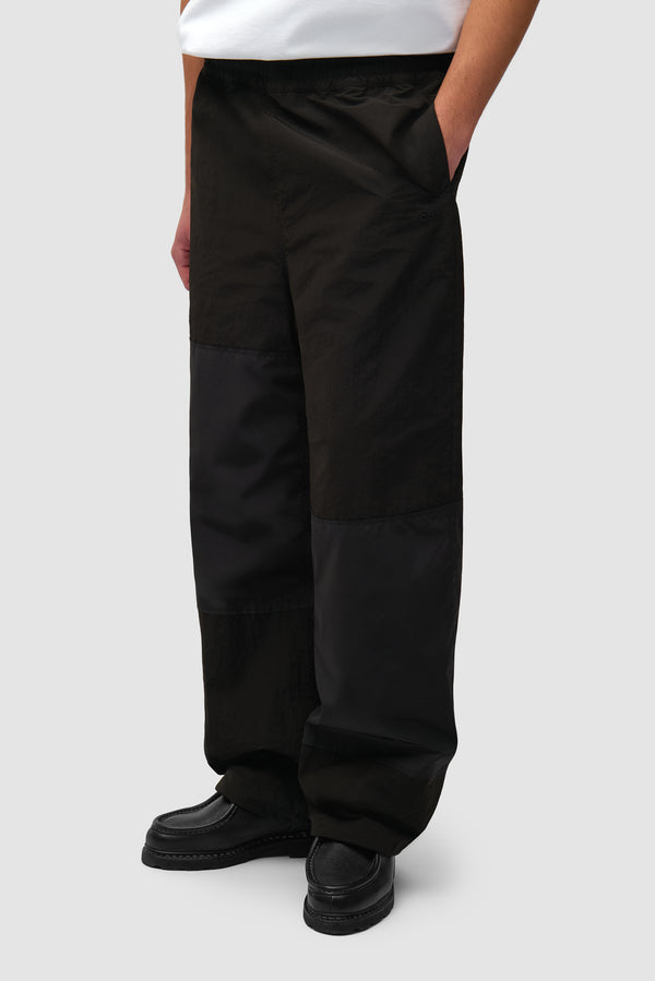 Squared Track Pants in Black worn by a model, half-body side view