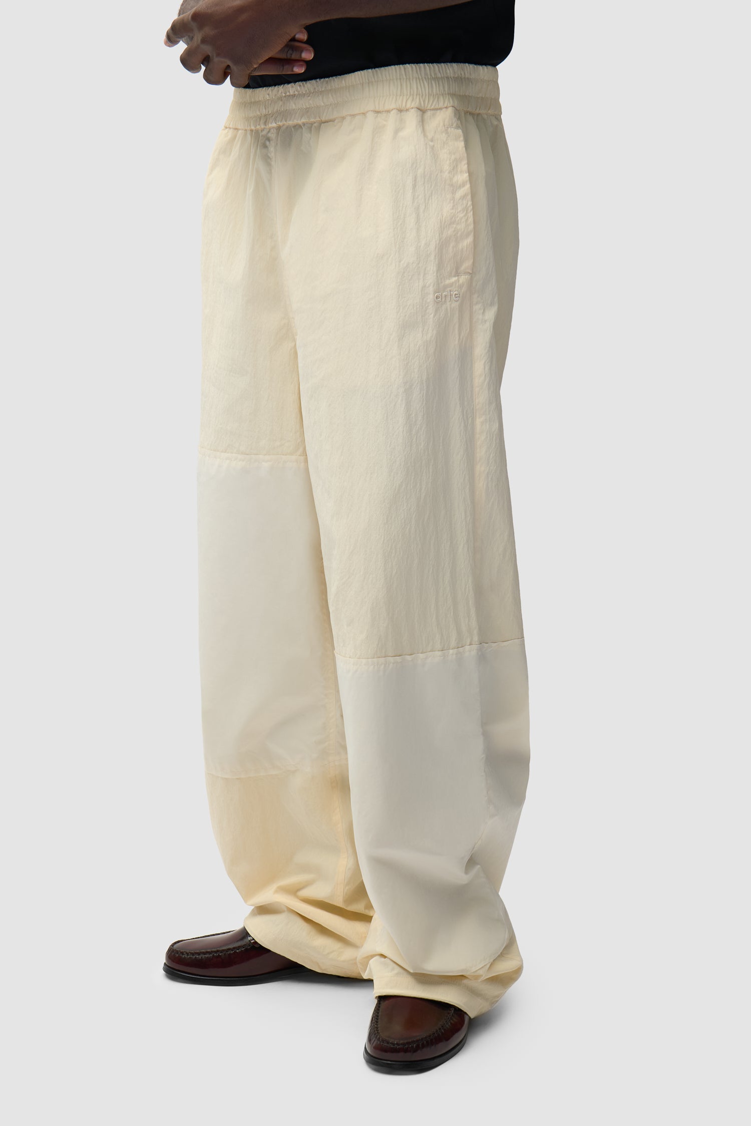 Pantalon de survêtement carré couleur crème porté par un mannequin, vue de profil à mi-corps