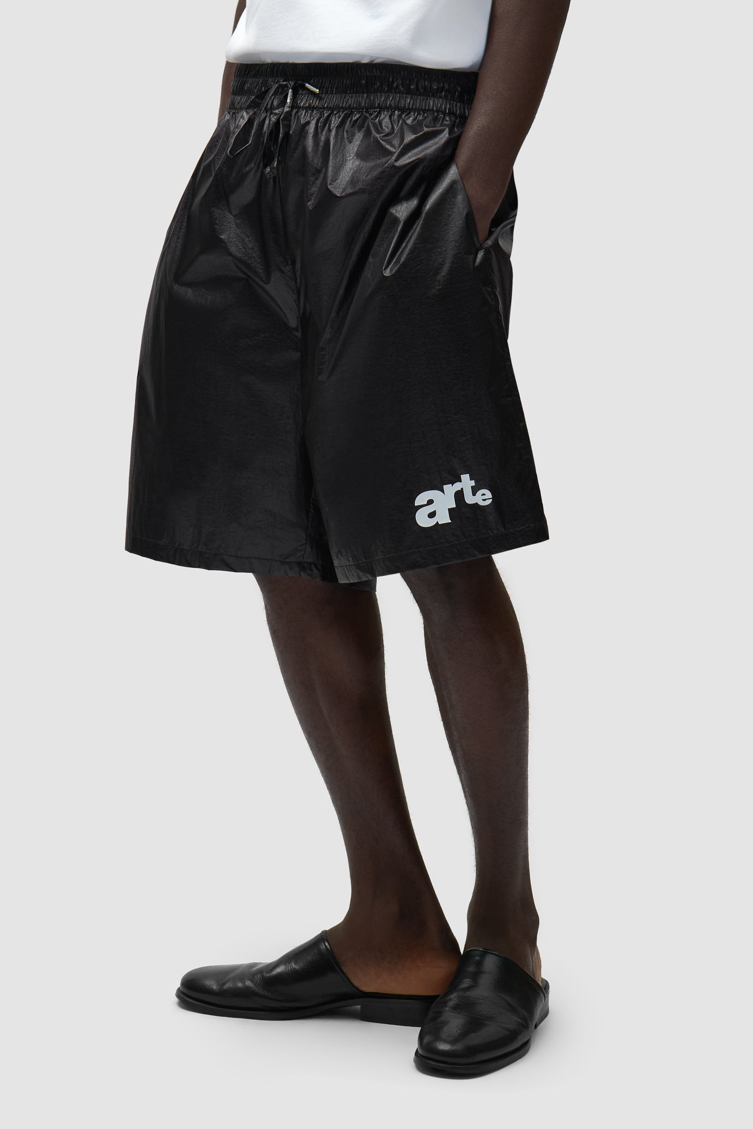 Short à grand logo noir porté par un mannequin, vue de profil à mi-corps