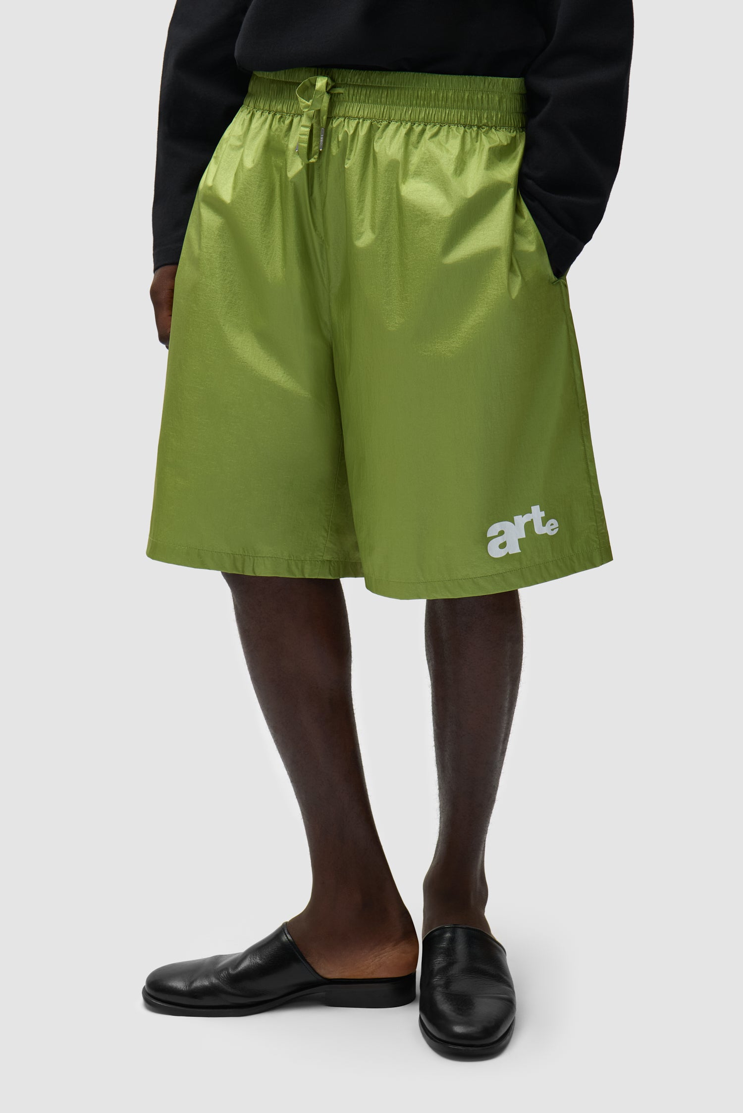 Short à grand logo vert porté par un mannequin, vue de face à mi-corps