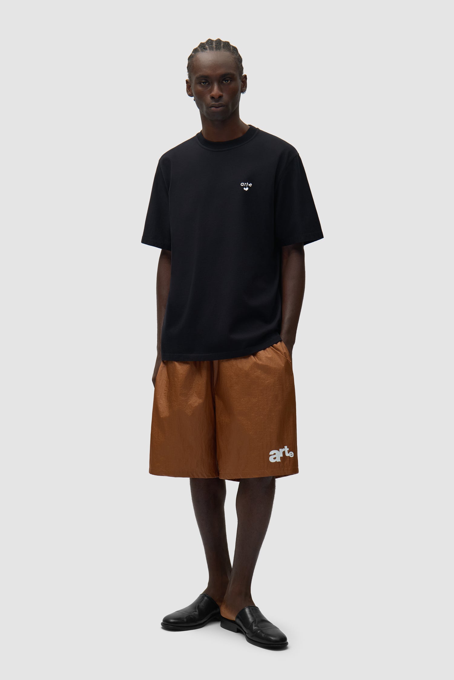 Short à grand logo orange porté par un mannequin, vue de profil en pied